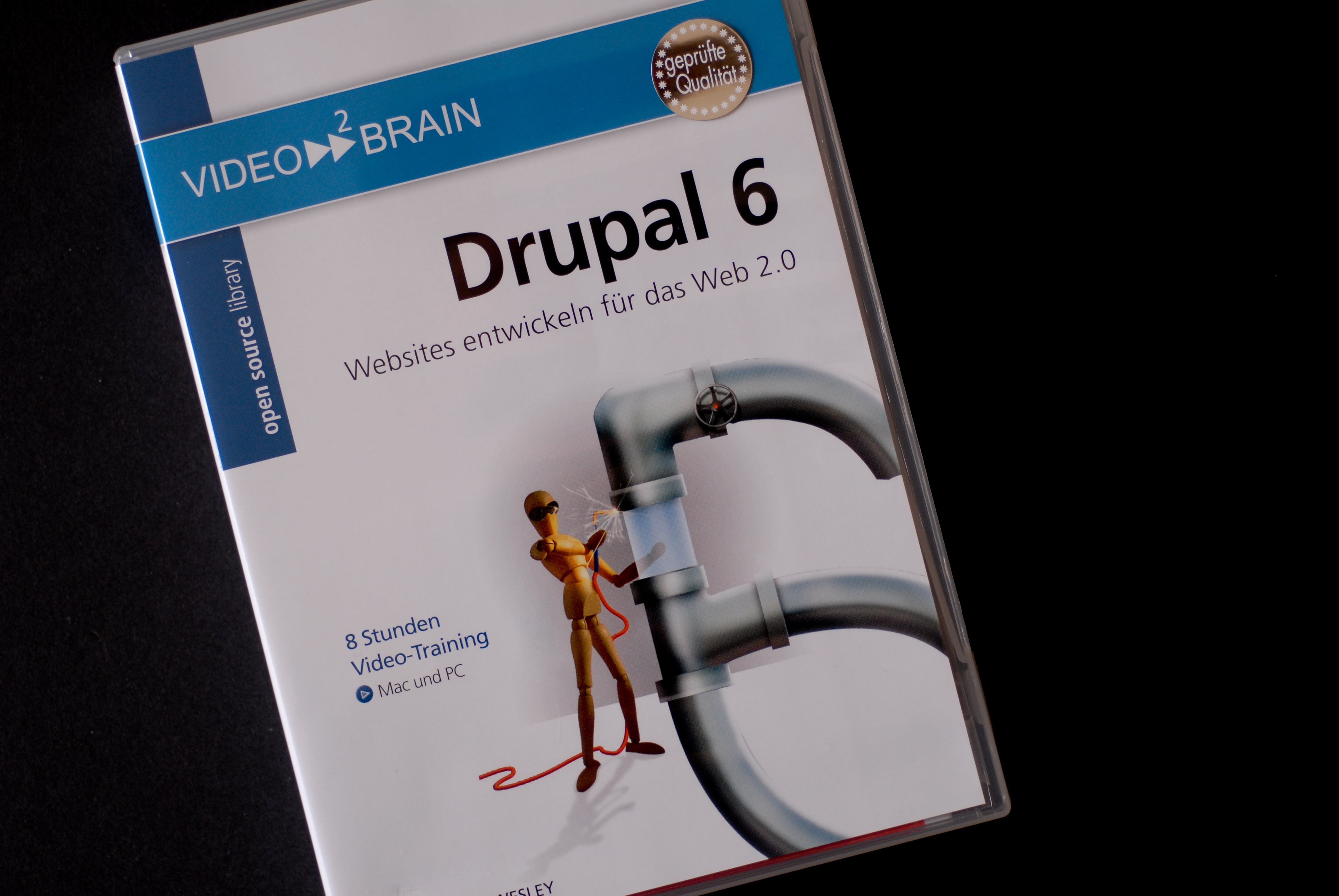 DVD case for "Drupal 6" video training by Video2Brain, featuring a graphic of pipes and a wooden figure.