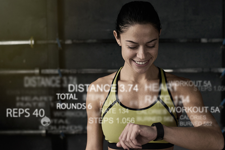 A woman in workout clothes checks her smartwatch, with fitness stats overlaid on the image.