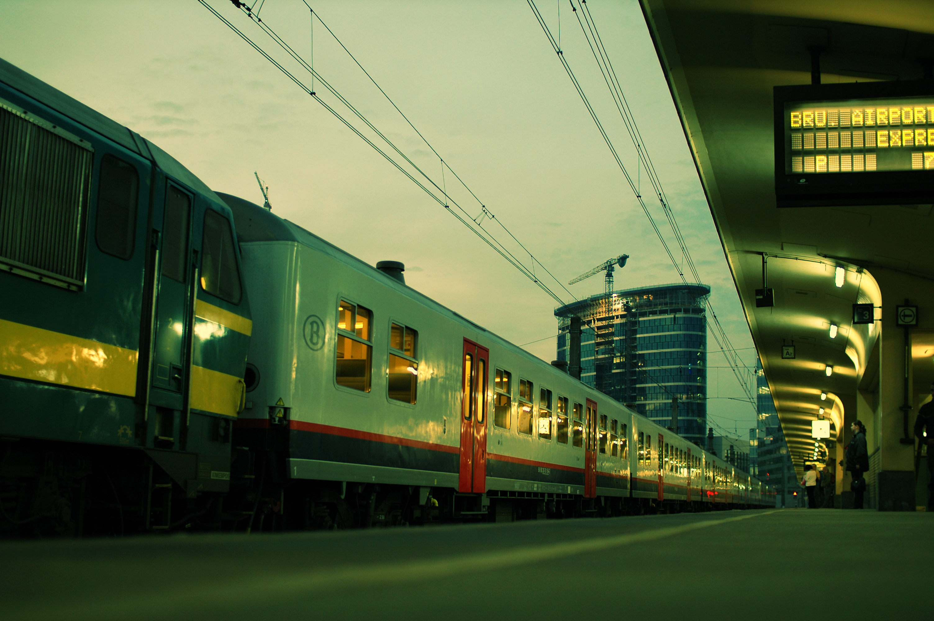 A train labeled "Airport Express" is stopped at a platform, with passengers waiting nearby.