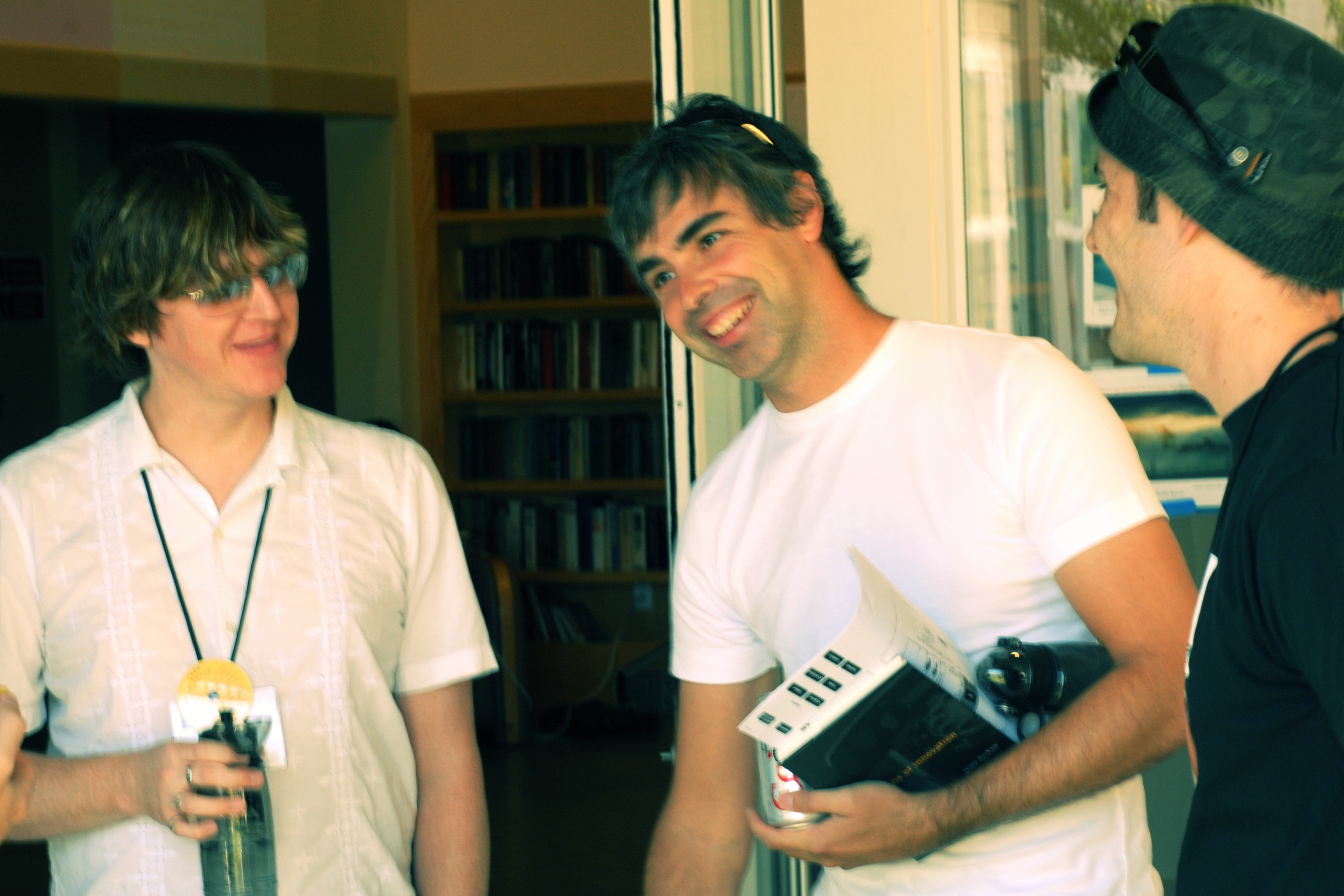 Three men stand together, smiling and talking.