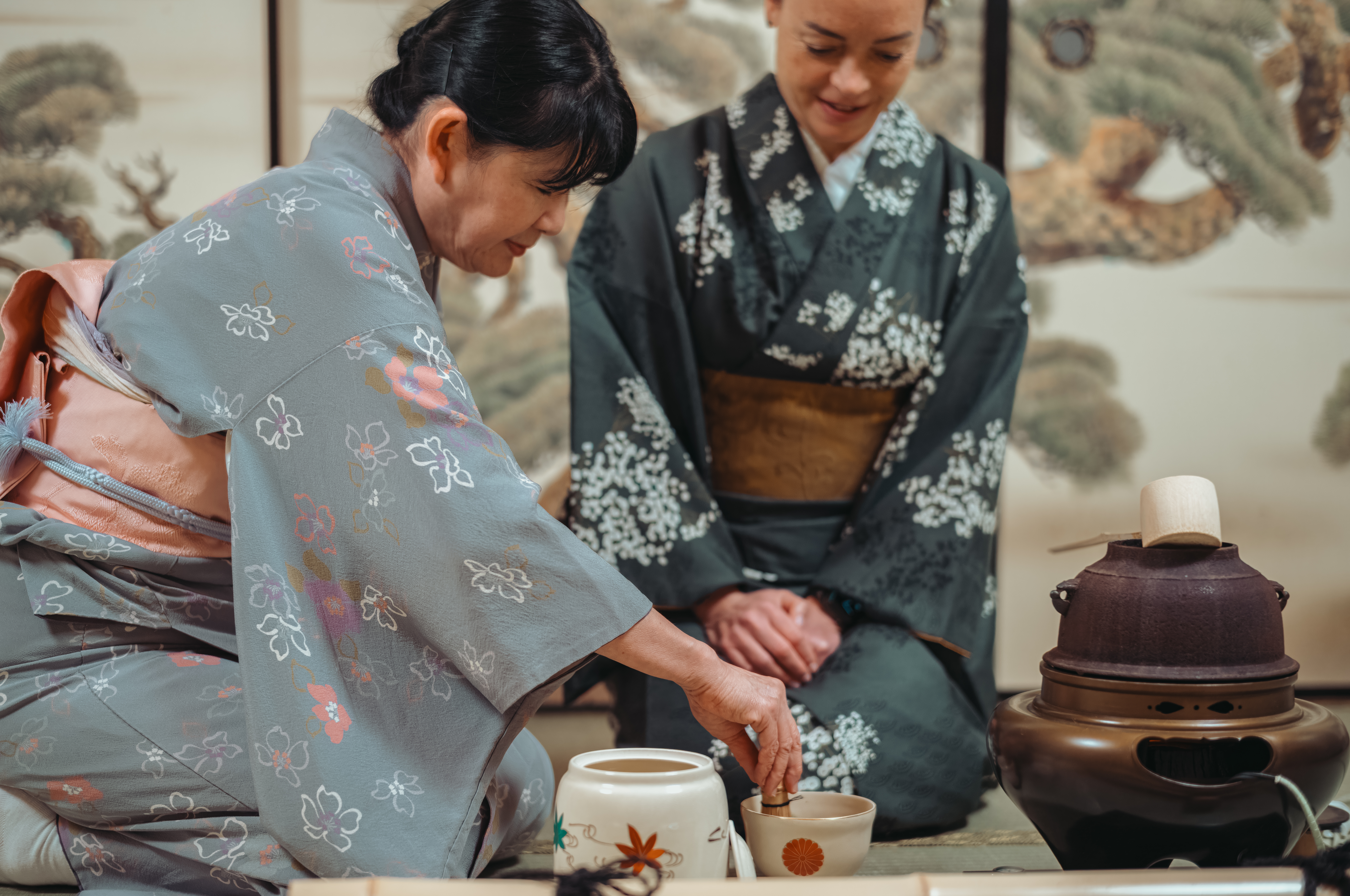 A woman in a kimono prepares matcha tea while another woman watches during a traditional Japanese tea ceremony in Tokyo.