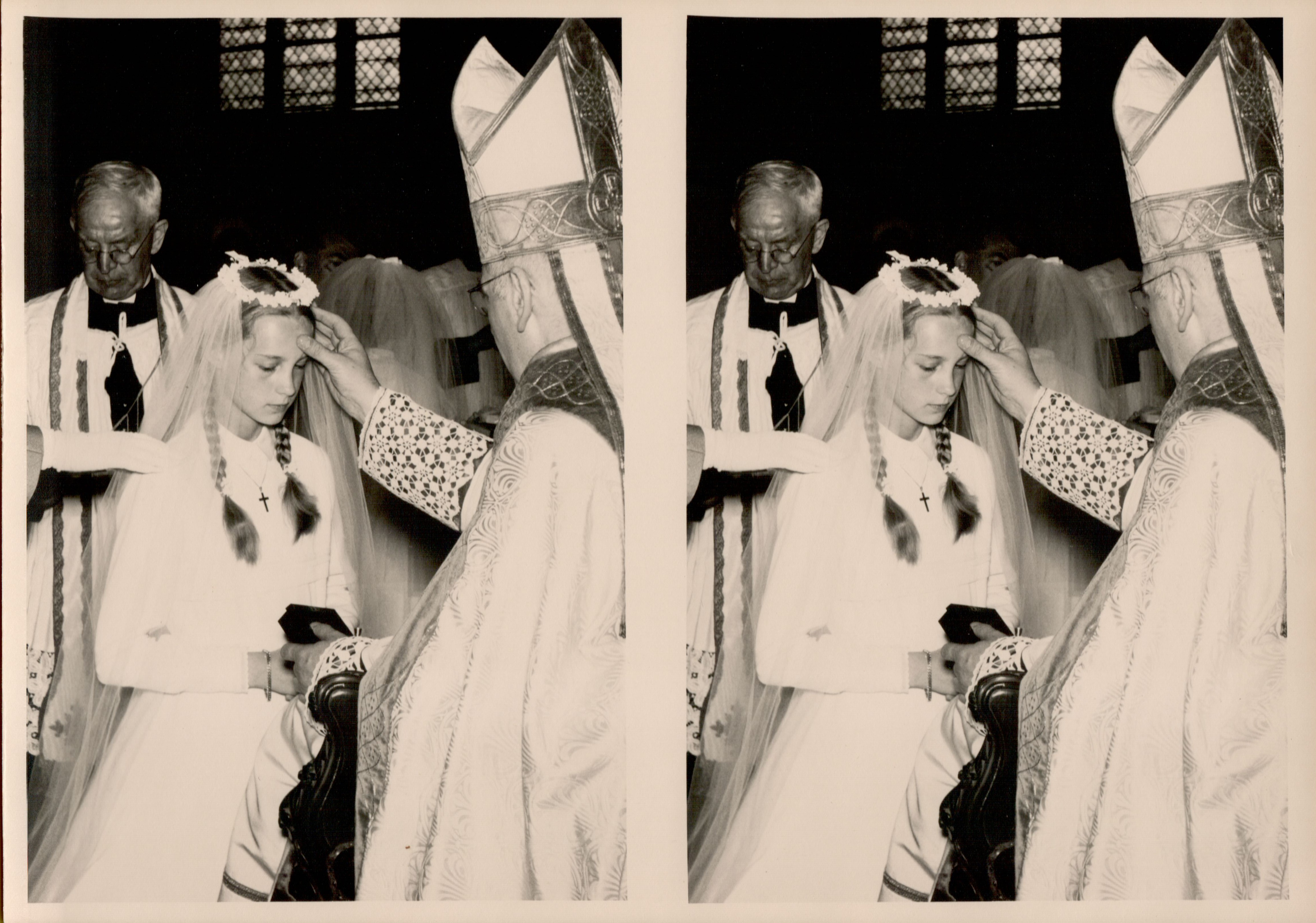 A bishop blesses a young girl in a white dress and veil during her First Holy Communion ceremony.