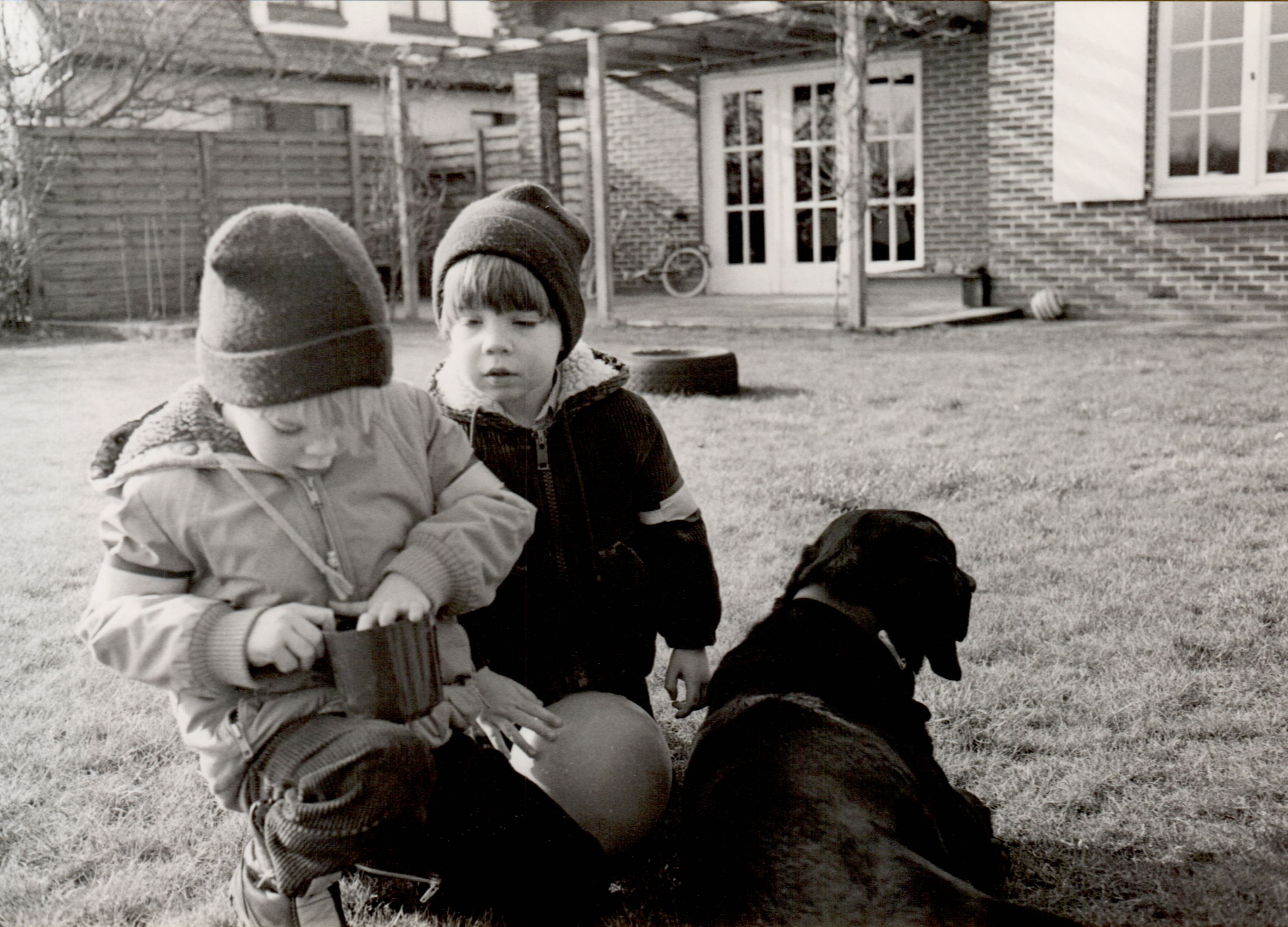 Two children in winter clothes play outside.