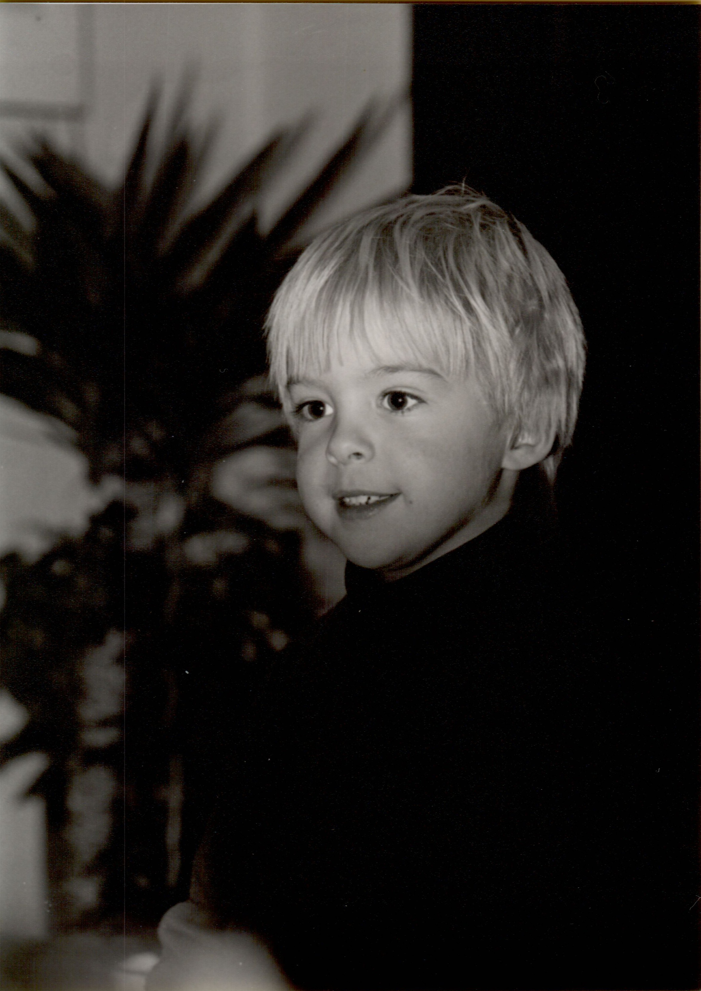 A young child smiles, possibly reacting to receiving a flashlight as a fifth birthday gift.