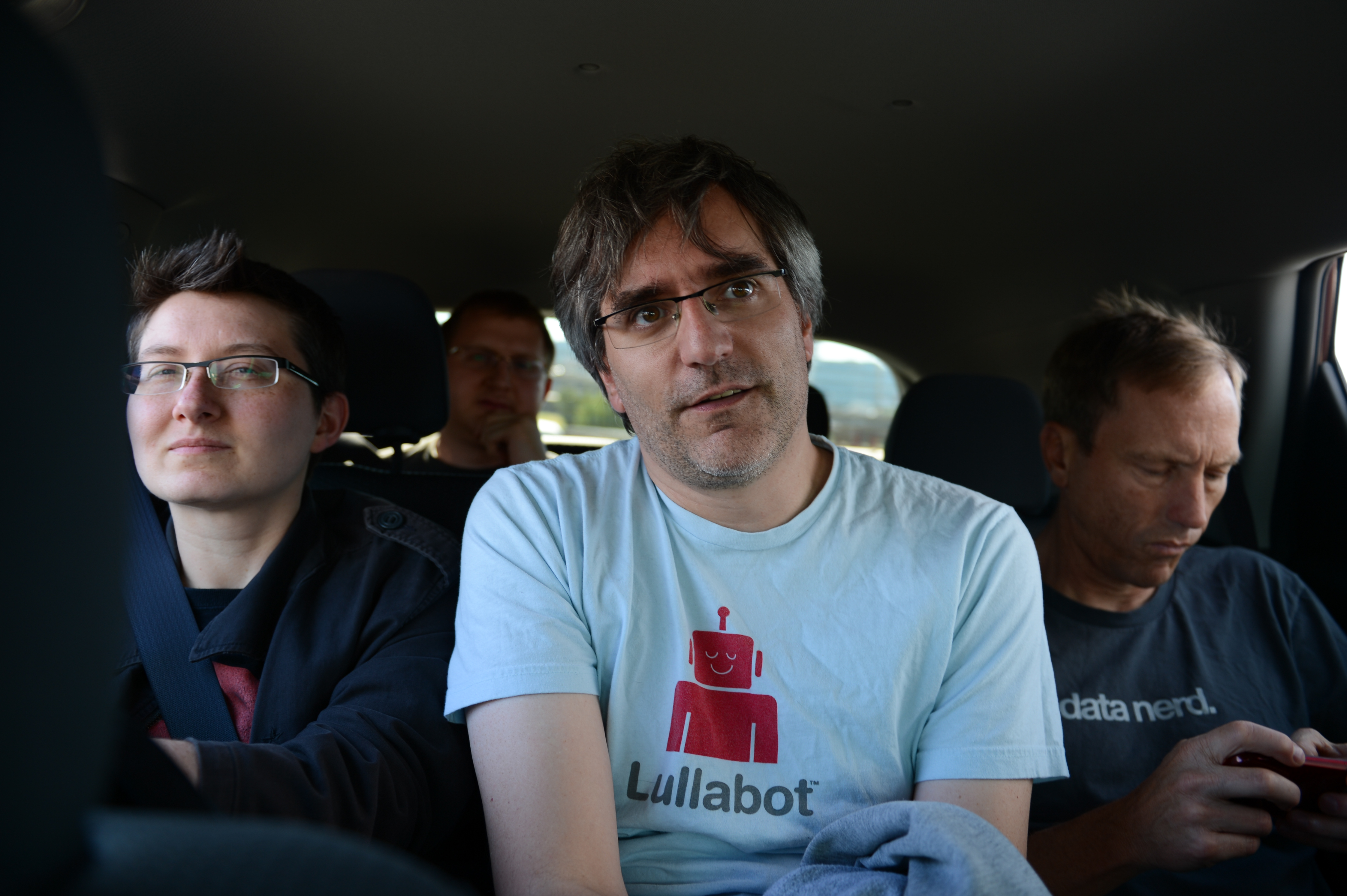 Four people sitting in a car, with one person in a "Lullabot" shirt looking at the camera.