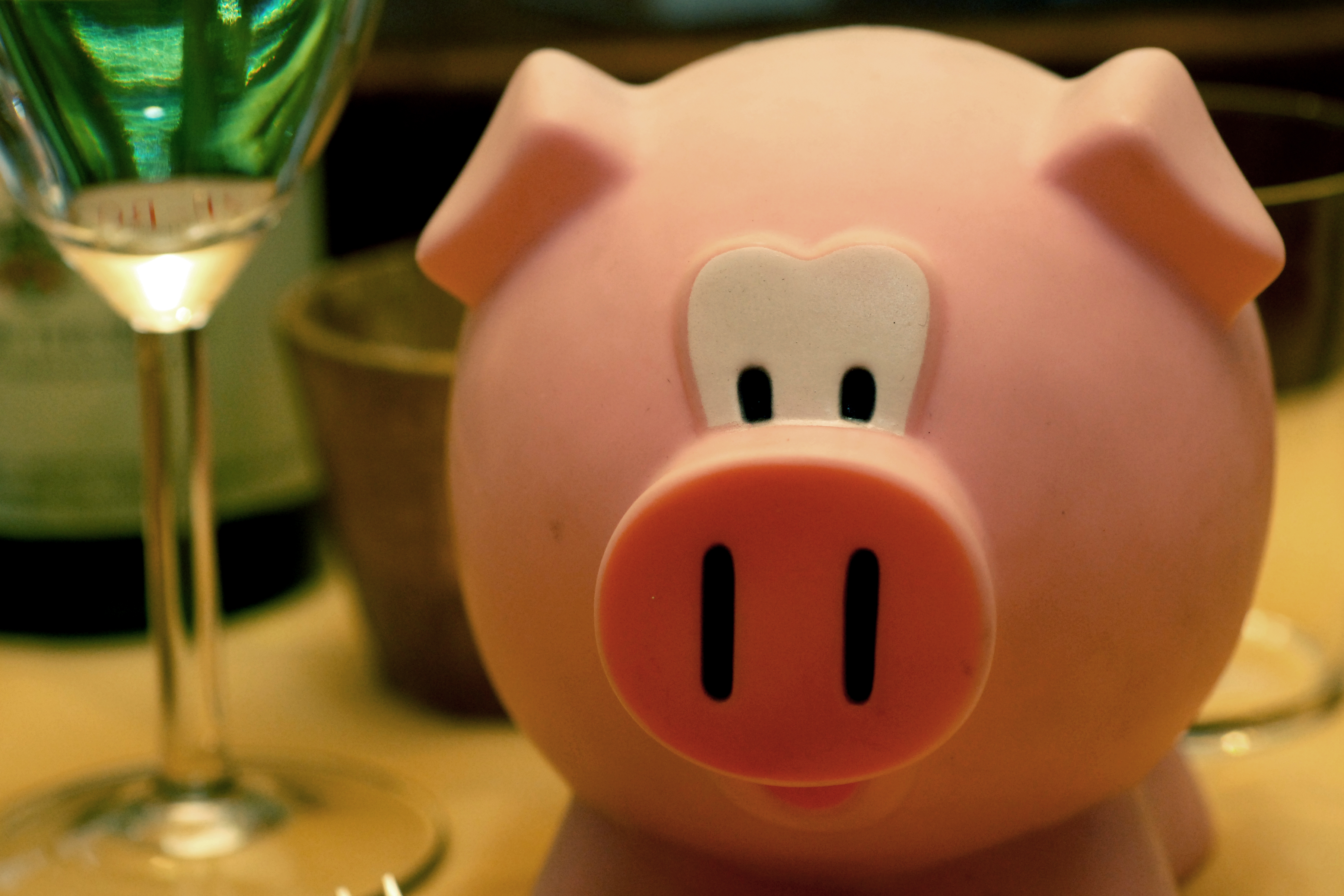 A pink pig-shaped container used to store New Year&#039;s resolutions, placed on a table with glasses nearby.