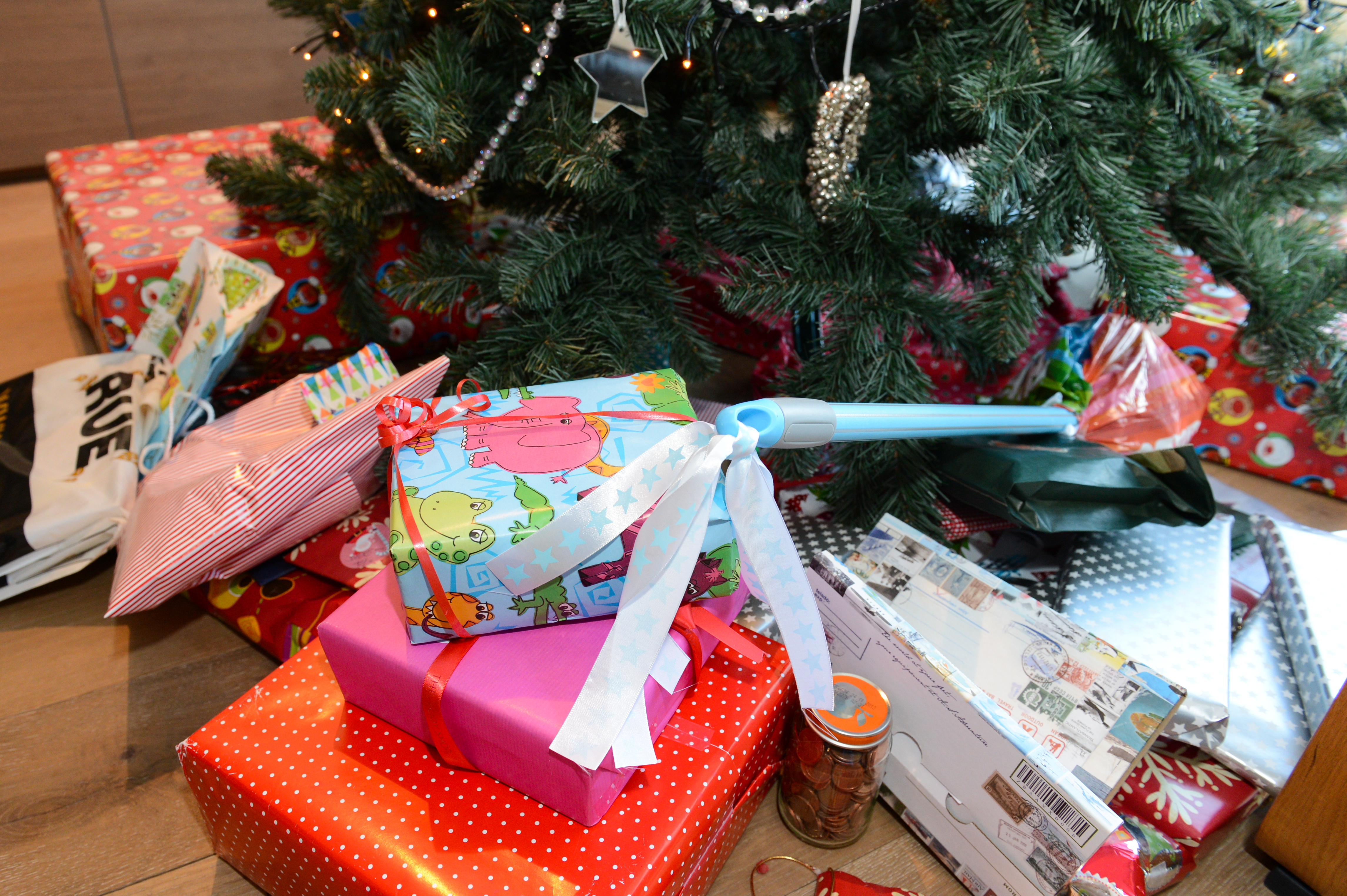 A decorated Christmas tree with wrapped gifts underneath, featuring colorful paper and ribbons.