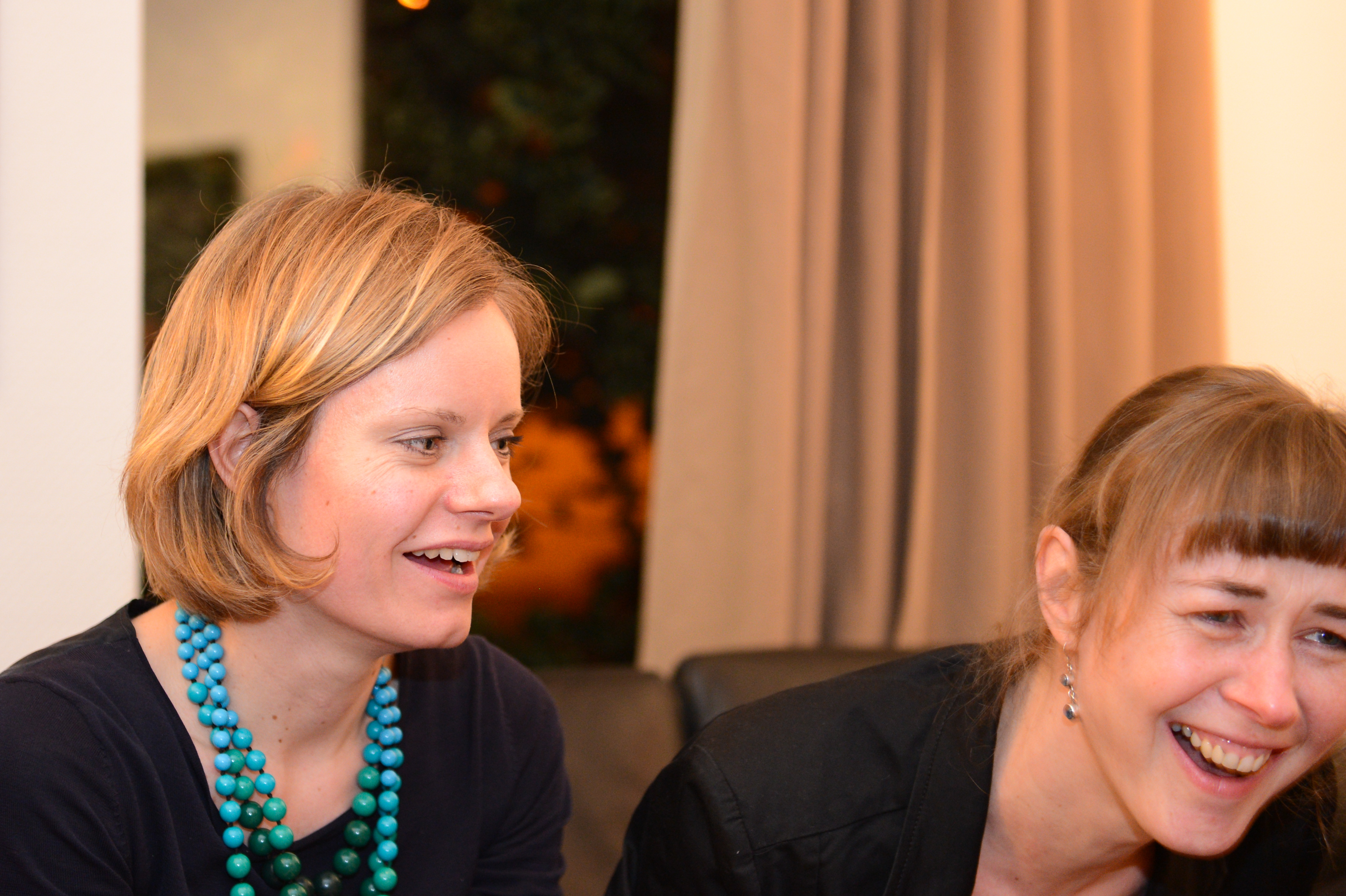 Two women laughing and enjoying a conversation at a New Year's Eve party.