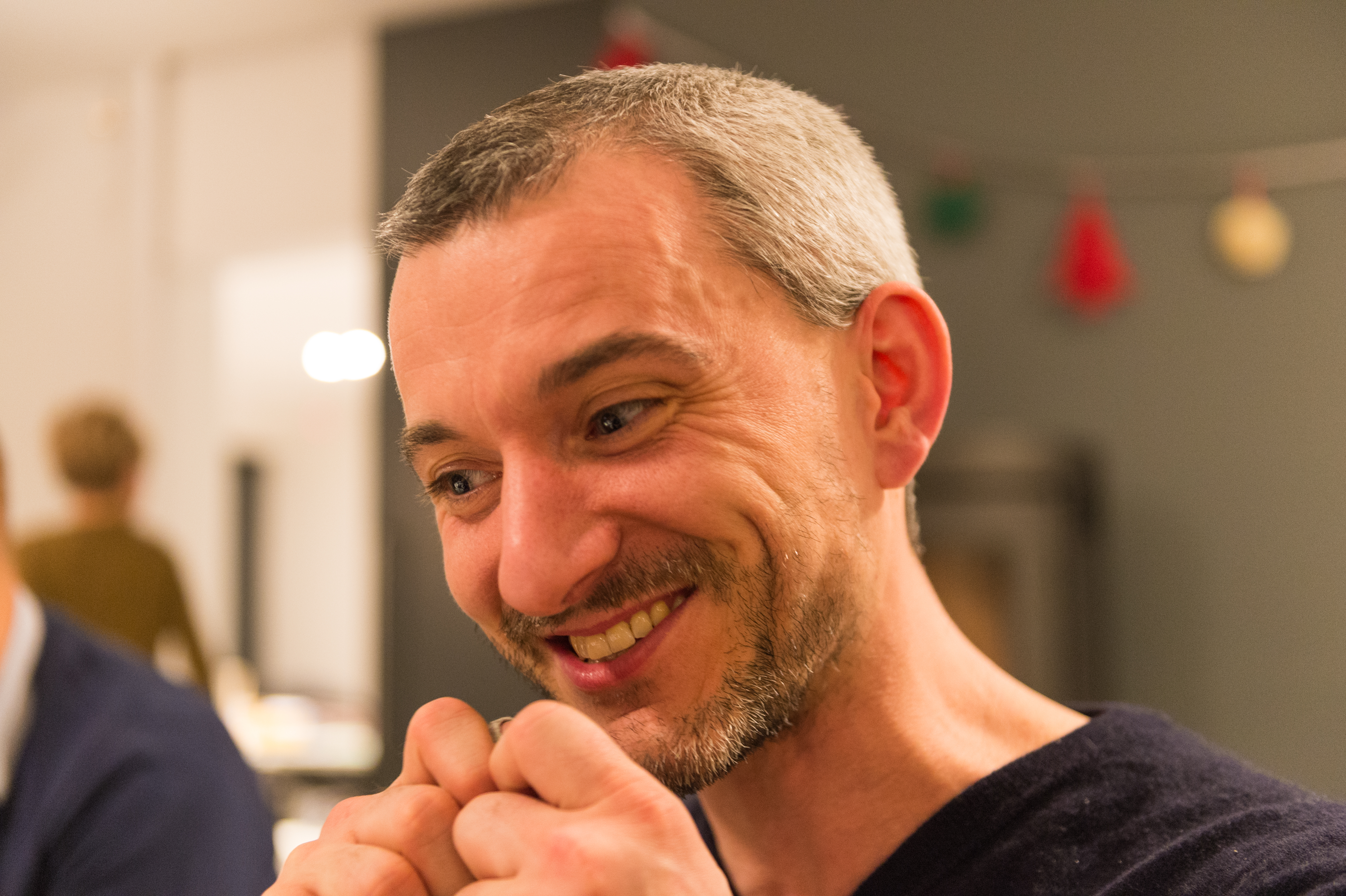 A smiling man at a New Year's Eve party, looking engaged in conversation with hands clasped together.