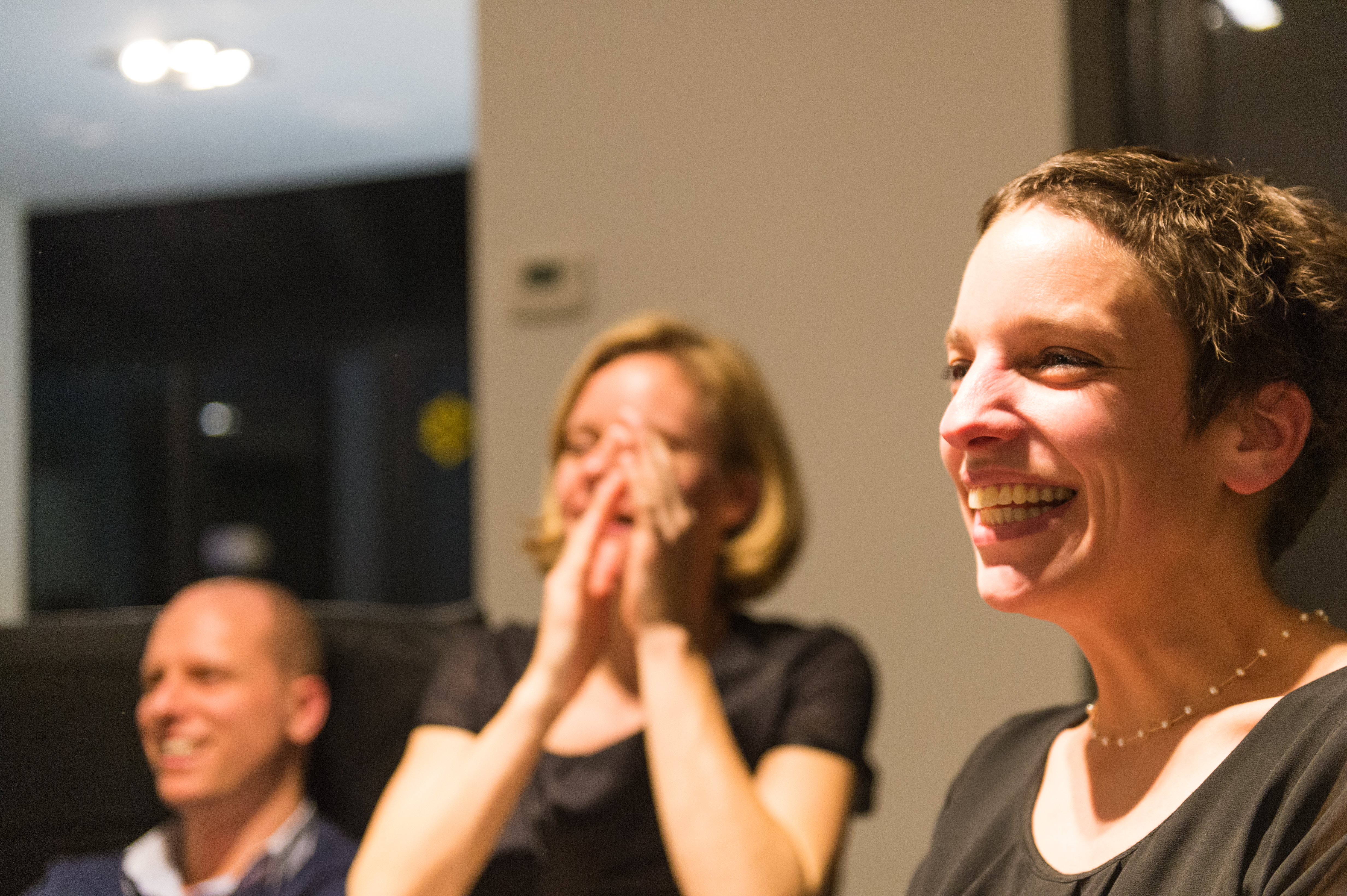 Three people laughing and smiling at a New Year's Eve party, enjoying the moment together.