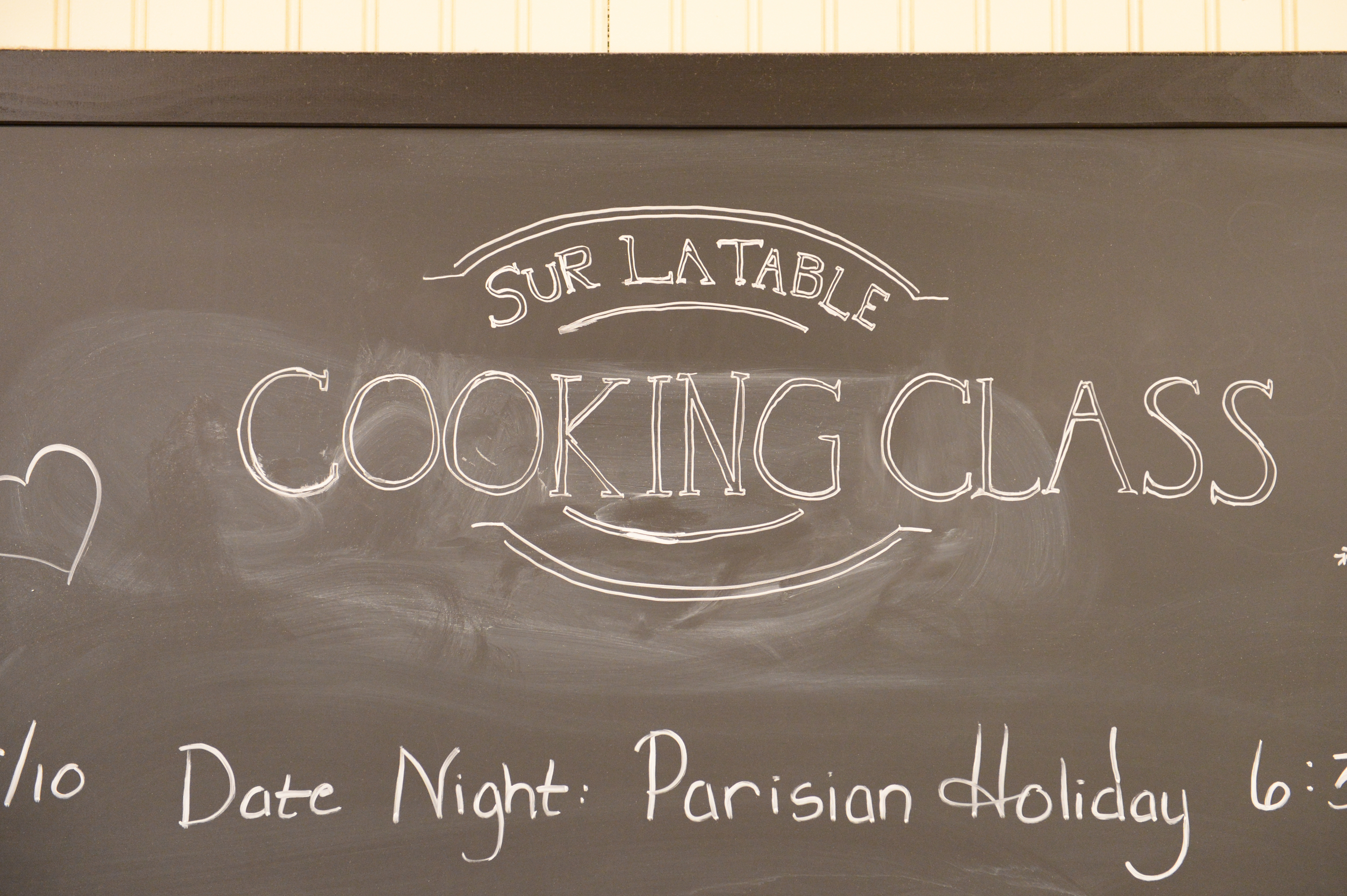 A chalkboard sign displays "Sur La Table Cooking Class" with additional event details written below.