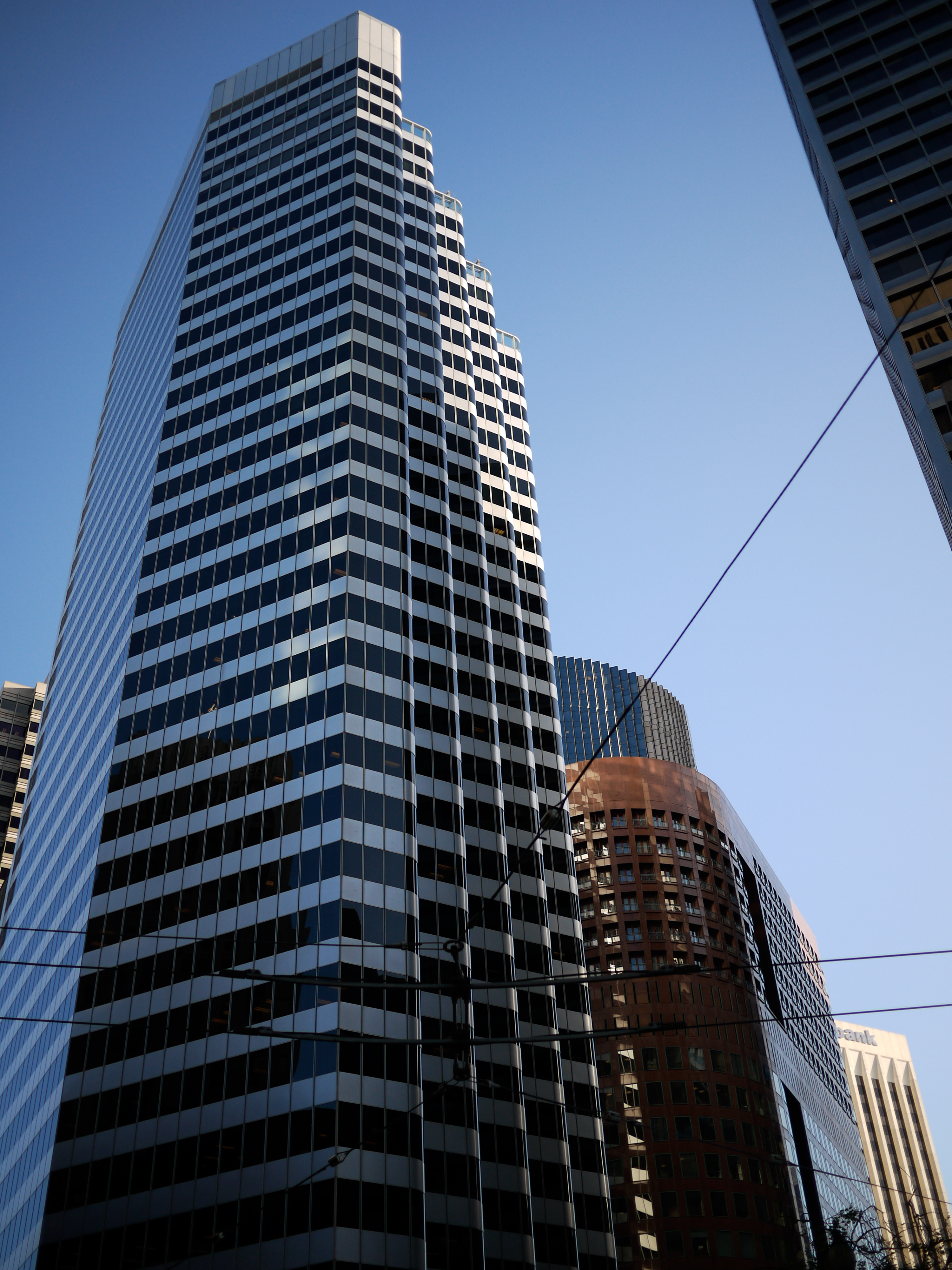 Tall modern skyscrapers with reflective glass windows in San Francisco, viewed from below against a clear blue sky.