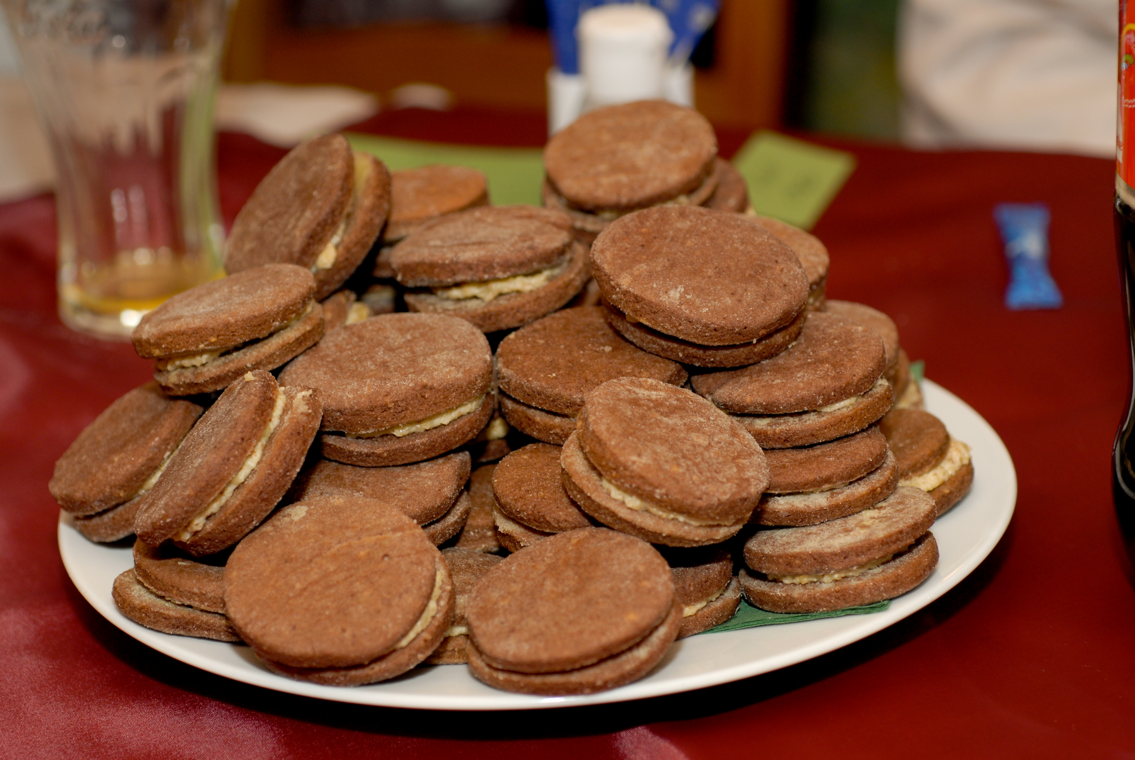 A plate of chocolate sandwich cookies with cream filling, stacked on a table at a wedding reception.